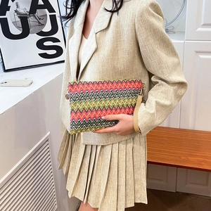 Detail view of a colorful rainbow woven clutch with zigzag patterns and tan leather handle