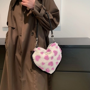 Close-up of heart-shaped plush bag with pink heart pattern and embroidered label