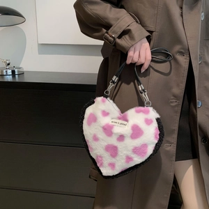 Detail of heart-shaped faux fur handbag with pink heart pattern and black fur trim accent