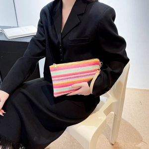 Detail of a rainbow striped woven clutch with gold zipper and stylish wrist strap