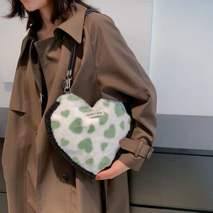 Detail of white plush heart-shaped handbag with green hearts and black shoulder strap