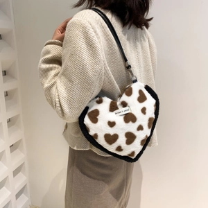 Close-up of heart-shaped plush bag with brown heart patterns and slogan tag