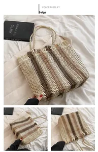 Dettaglio della borsa tote in paglia a righe beige e marroni con bordi sfrangiati