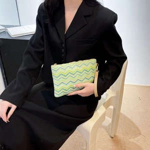 Detail of colorful woven clutch bag with wave patterns and golden zipper closure