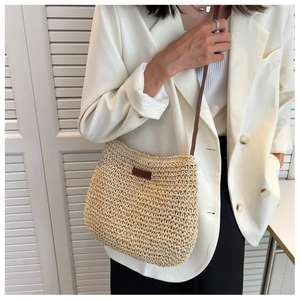 Détails du tissage d'un sac bandoulière en paille beige avec écusson décoratif brun