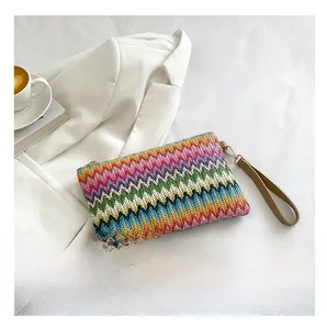 Detail of multi-color woven knit clutch featuring a zigzag texture and khaki hand strap