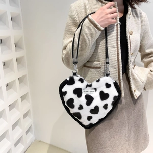 Detail of heart-shaped plush shoulder bag with black and white heart print and logo label