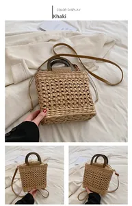 Detail view of khaki straw handbag featuring dark brown round handles and drawstring lining