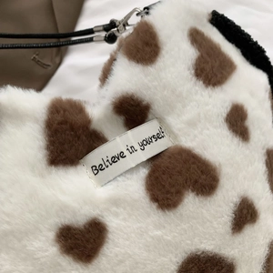 Detailed close-up of heart-patterned plush bag showing Believe in yourself tag