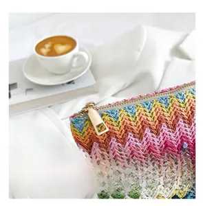 Detail of a rainbow woven pouch featuring a smooth gold zipper and vibrant wave pattern