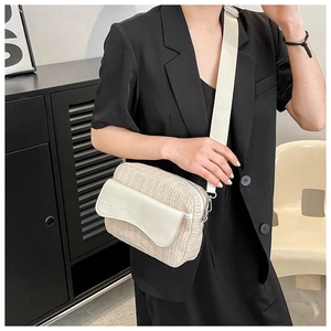 Detail of woven straw crossbody bag with white leather flap and adjustable strap