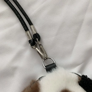 Detail of a plush heart bag showing metal lobster clasp and black leather strap textures