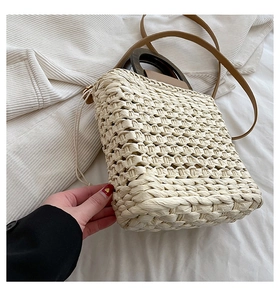 Detail of the woven straw texture and round wooden handle on this cream fashion tote bag