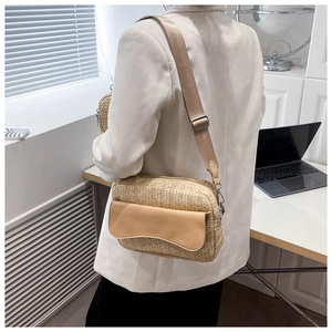 Detail of handwoven straw crossbody bag featuring a brown leather flap and adjustable strap