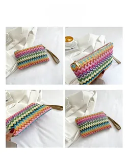Detail view of rainbow woven clutch bag featuring zigzag patterns and a gold zipper