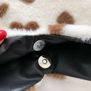 Detail view of white and brown faux fur bag with silver magnetic snap closure
