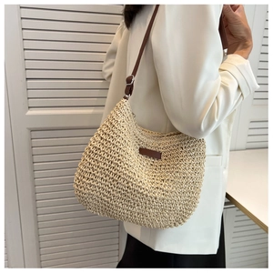 Detail showing the adjustable brown leather strap and hand-woven texture of the straw bag