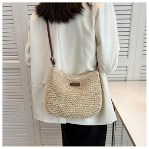 Détail d'un sac bandoulière en paille tressée avec bandoulière marron pour l'été
