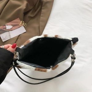 Overhead view of the plush heart bag showing cow print texture and black inner lining