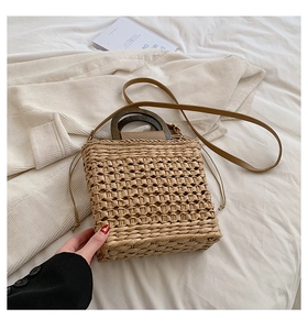 Detail of woven straw handbag featuring vintage wood handles and a drawstring inner pouch