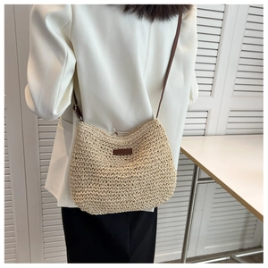 Modèle portant un sac à bandoulière en paille tressée avec sangle et patch en cuir marron