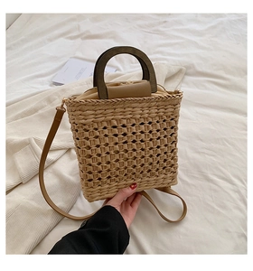 Straw tote bag detail with dark wood handles and woven mesh texture on white fabric