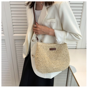 Detail shot of natural straw weaving texture and brown leather patch on summer crossbody bag