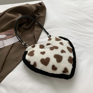Close-up of white plush heart-shaped bag with black trim and 'Believe in yourself' label