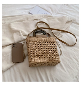 Detail of straw woven handbag featuring a round wooden handle and drawstring closure