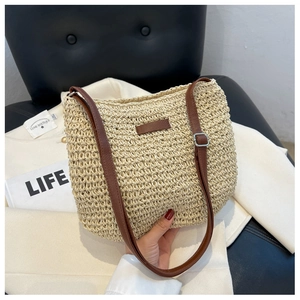 Détail du sac en paille tressée beige avec bandoulière en cuir marron et boucle réglable