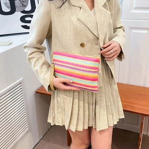 Rainbow woven striped clutch bag with a wristlet and gold zipper held by a model