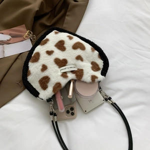 Macro detail of heart-shaped plush bag interior with phone, lipstick and makeup accessories