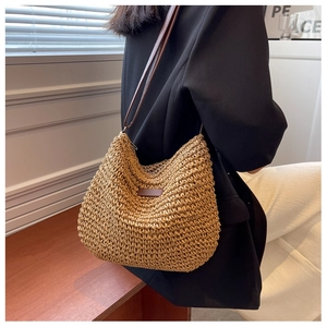 Détail d'un sac à bandoulière en paille tissé main avec écusson en cuir chic