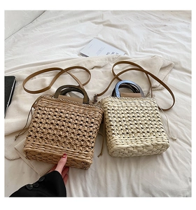 Detailed view of woven straw handbags featuring round wooden handles and drawstring liners