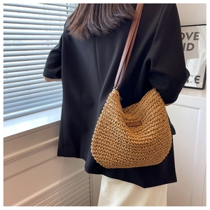 Texture détaillée d'un sac bandoulière en paille tissée avec lanière en cuir marron