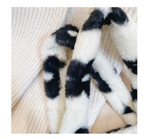 Gros plan sur la texture pelucheuse à motif vache noir et blanc de la bandoulière