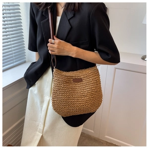 Détail d'un sac à bandoulière en paille tressée avec empiècement en cuir marron