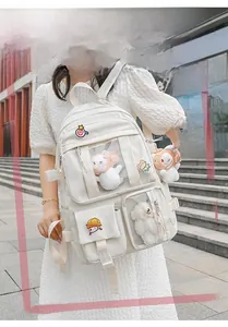 Outdoor model wearing a cream-colored Ita Bag with transparent PVC window and cute pins