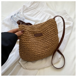Close-up of the dense woven straw texture and premium brown leather patch on the crossbody bag