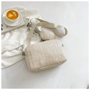 Detailed view of beige woven crossbody camera bag with small pouch and wide fabric strap