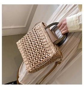 Detailed close-up of handmade straw woven handbag with solid wood handles and leather strap