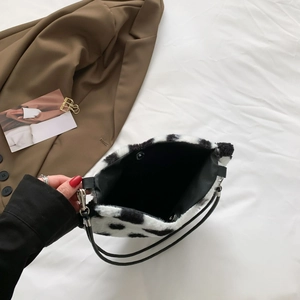 Furry cow print shoulder bag with black and white plush material and magnetic closure