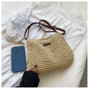 Détail du sac bandoulière en paille tressée avec lanière en cuir et boucle en métal