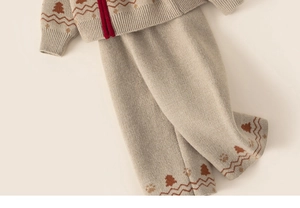 Detail of grey knit pants and sweater hem featuring brown holiday trees and red trim