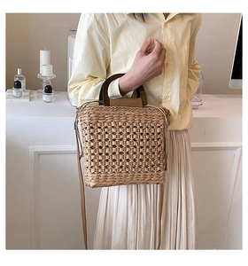 Detailed texture of hand-woven straw handbag with premium leather handles and shoulder strap