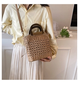 Close-up of a woven straw handbag with wood handle and a beige drawstring pouch