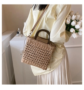 Detail view of woven straw texture and dark brown wooden handle on the tote bag