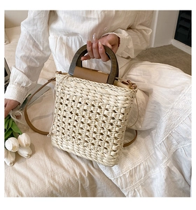 Detailed view of straw handbag with wooden handle and leather strap for summer