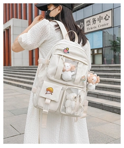 Detail view of cream school backpack with transparent windows and cute badges for dolls