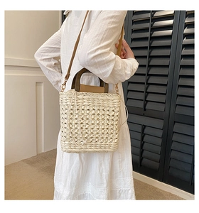 Detail of hand-woven straw crossbody bag with wooden handle and leather strap